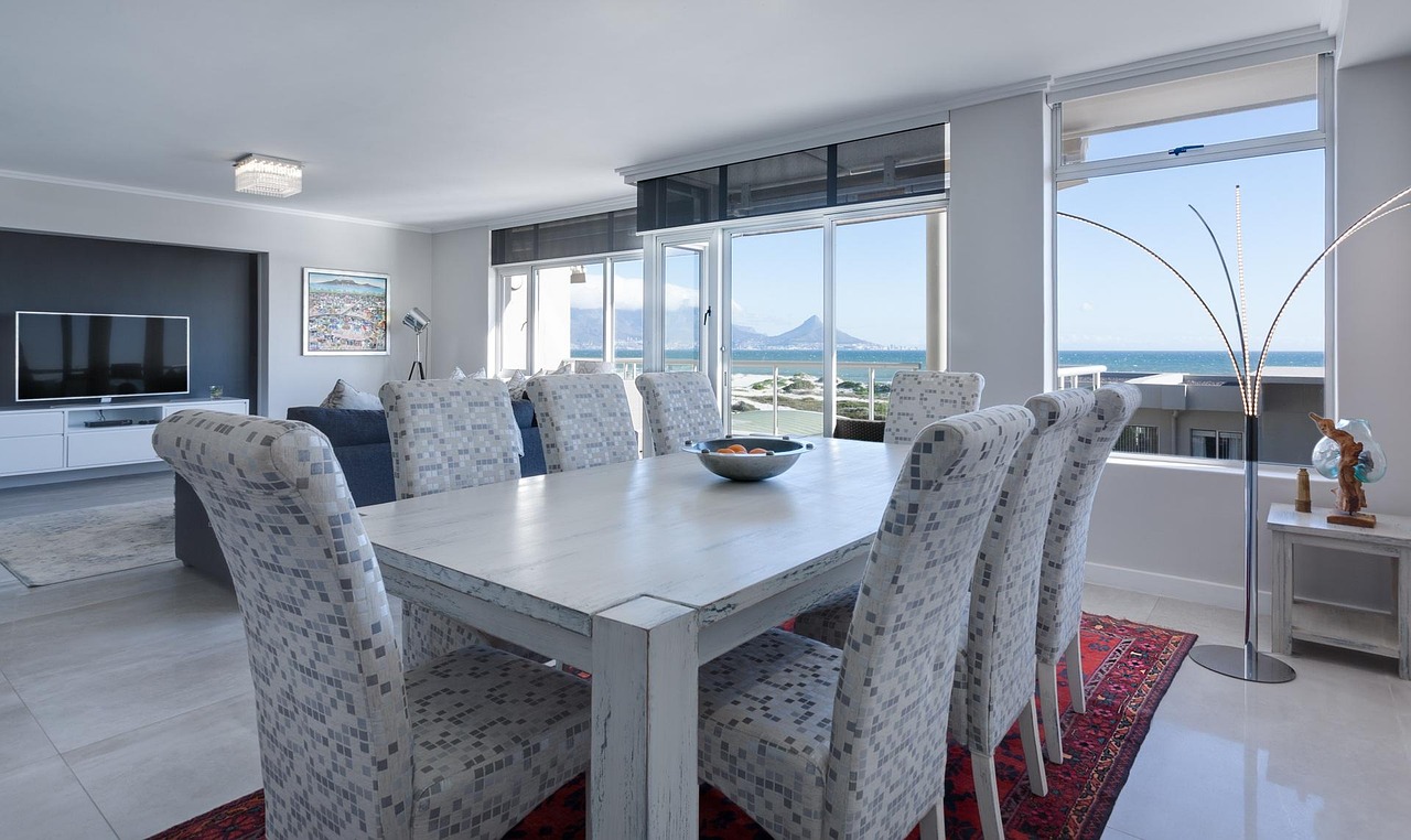 A bright apartment living and dining room with large windows and a view of the sea