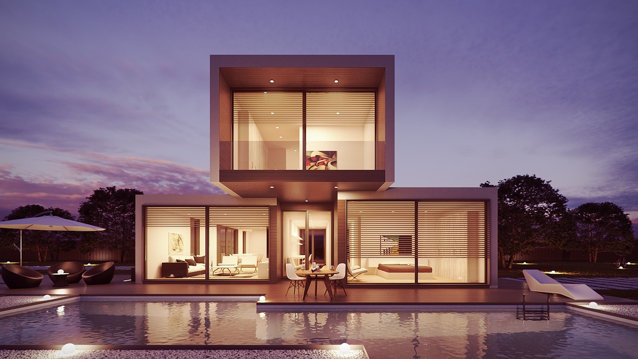 A modern house at dusk with warm light in every window and a pool reflecting the evening sky